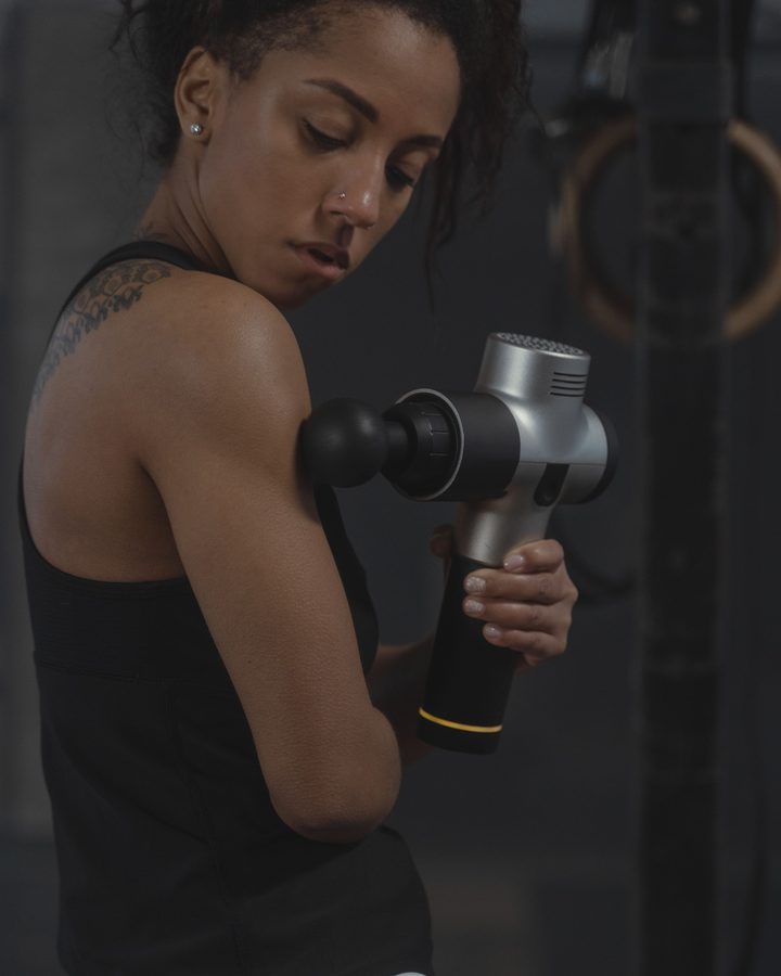 Athlete using a percussive massage device after training